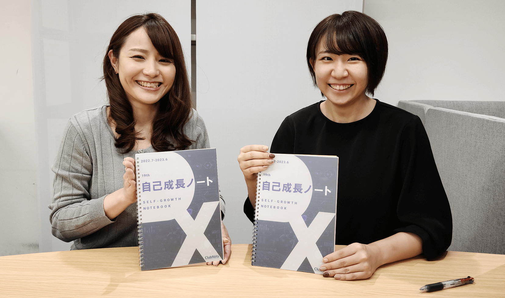 笑顔で自己成長ノートを手に持つ女性社員の方々